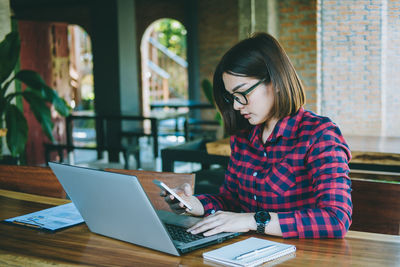 Woman using phone while sitting on table