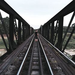 Rear view of man standing on railway bridge against clear sky