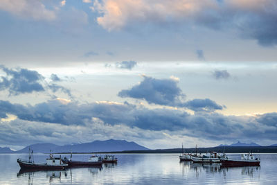 Sailboats moored in sea against sky