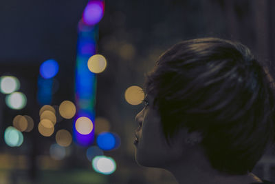 Rear view of woman standing on illuminated city street at night