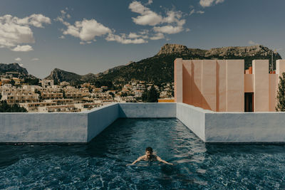 Man swimming in pool by sea against sky