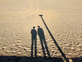 Shadow of people by street light on sand at beach