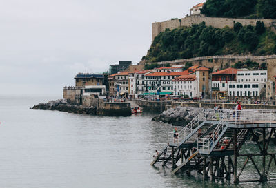 Buildings by sea against sky in city