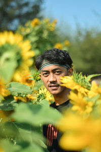 Portrait of young man against yellow flowering plants