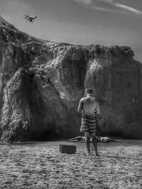 Man standing on rock formation in sea