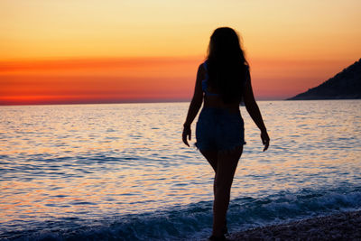 Full length of woman standing on beach during sunset