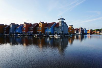 Buildings by river against sky