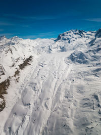 Scenic view of snow covered mountains against blue sky