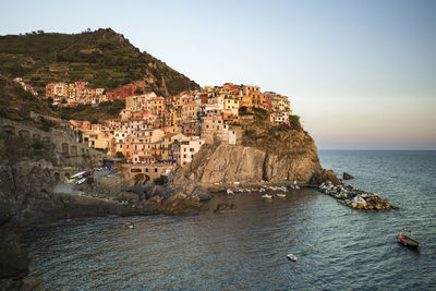 Houses on rock formation at manarola by sea against clear sky