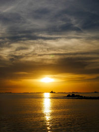 Scenic view of sea against dramatic sky during sunset