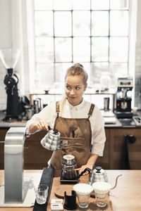 Female barista looking away while preparing coffee at cafe counter