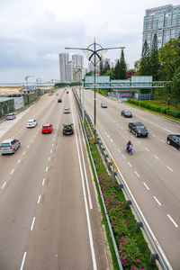 Vehicles on highway in city against sky