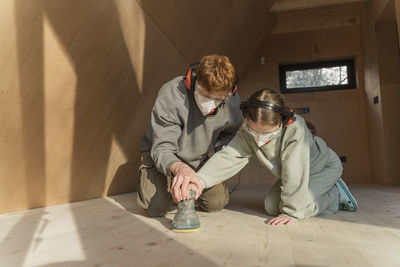 Father and daughter sanding the floor in their new eco house