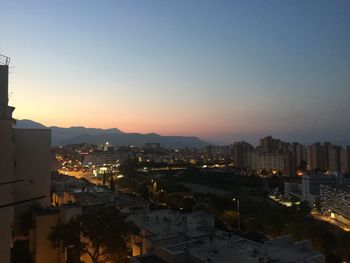 High angle view of illuminated city buildings against sky during sunset