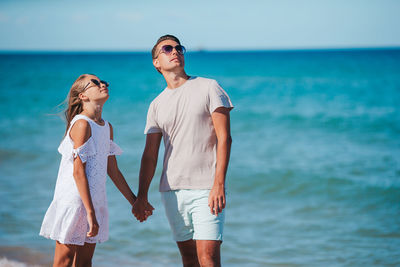 Father and daughter standing against sea and sky