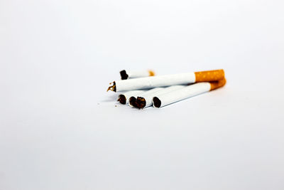 Close-up of cigarette smoking against white background