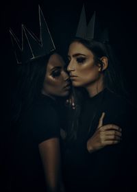 Beautiful women wearing paper crowns against black background