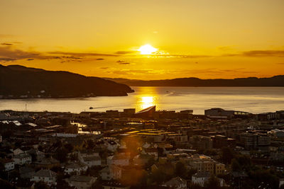 Aerial view of city by sea against orange sky