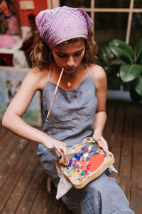 Woman mixing watercolor paints while sitting on boardwalk