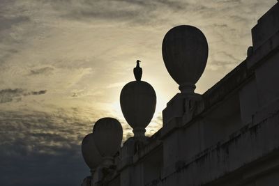 Low angle view of silhouette street light by building against sky