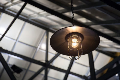 Low angle view of illuminated light bulb hanging on ceiling