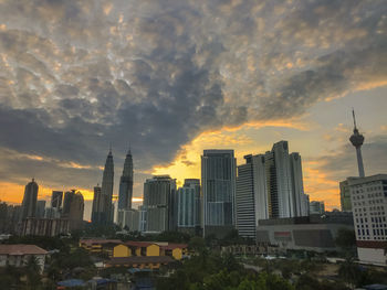 Buildings in city against cloudy sky during sunset