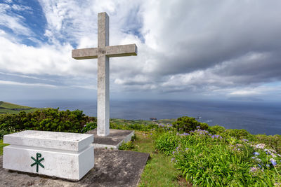 Cross in cemetery against sky