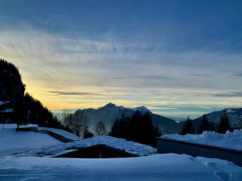 Snow covered landscape against sky during sunset