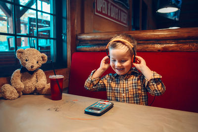 Boy listening music while sitting on table