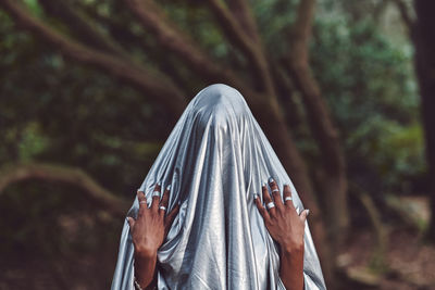 Close-up of woman wearing textile standing against tree