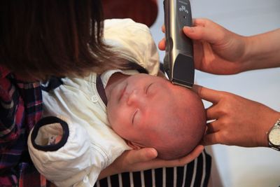 Man cutting hair of baby with electric razor