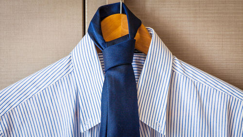 Close-up of shirt with necktie hanging on coathanger by window