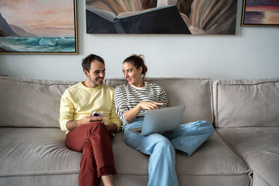 Young woman using laptop while sitting on sofa at home