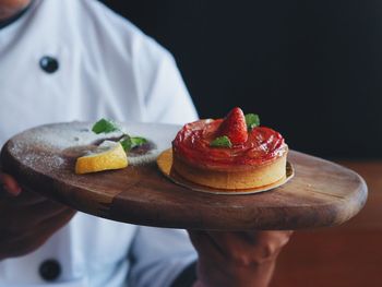 Midsection of chef holding strawberry tart