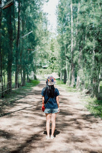 Full length rear view of man walking on road in forest