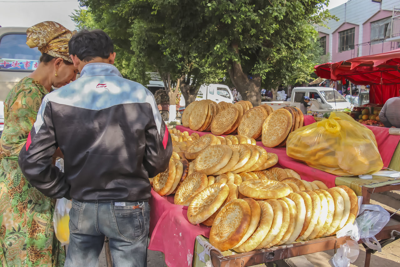 REAR VIEW OF PEOPLE AT MARKET