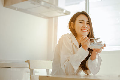 Portrait of a smiling young woman drinking glass