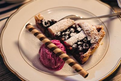 High angle view of cherry pie with ice cream and chocolate roll in plate