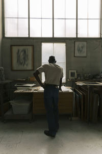 Rear view of male architect working at table in workshop