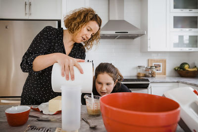 Mother teaching daughter to cook in kitchen at home