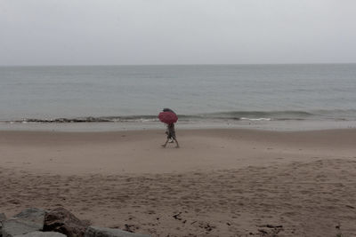 Rear view of woman on beach against sky