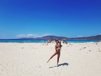 Full length of woman on beach against blue sky