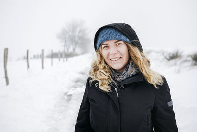 Blond woman standing on snow during vacations