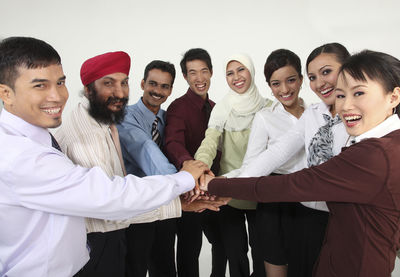 Portrait of colleagues with stacking hands against white background