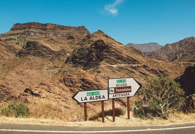 Road sign in desert against clear sky