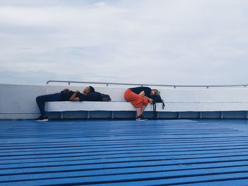 People sitting on floor against blue sky