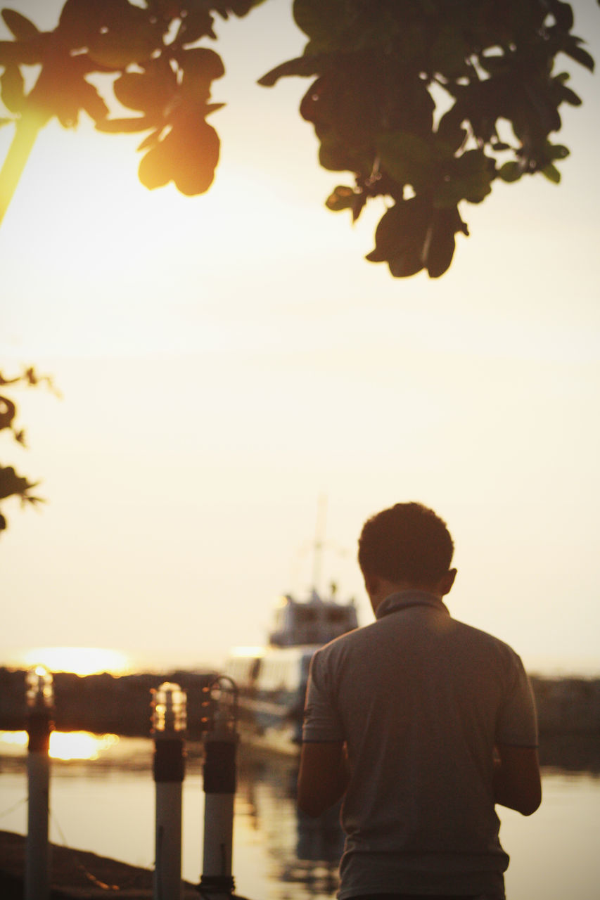 REAR VIEW OF SILHOUETTE MAN STANDING AGAINST SEA DURING SUNSET
