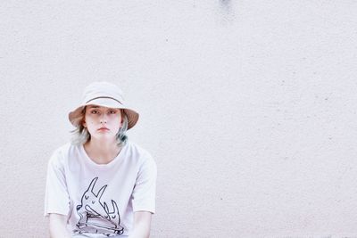 Portrait of beautiful young woman standing against wall