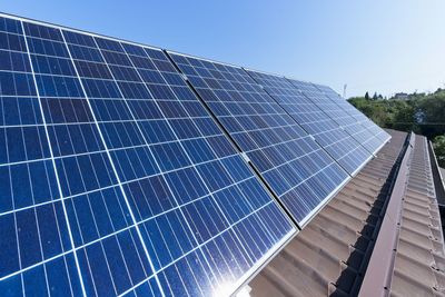 Close-up of solar panels against blue sky during sunny day