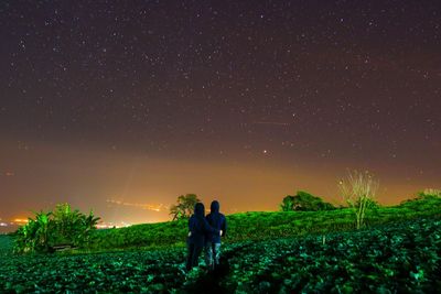 Rear view of men looking at star field against sky during night